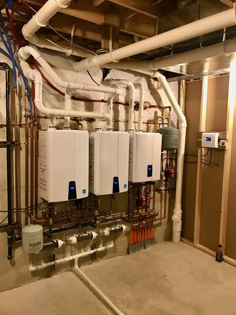 Bank of tankless water heaters with copper manifold piping installed by South County Mechanical